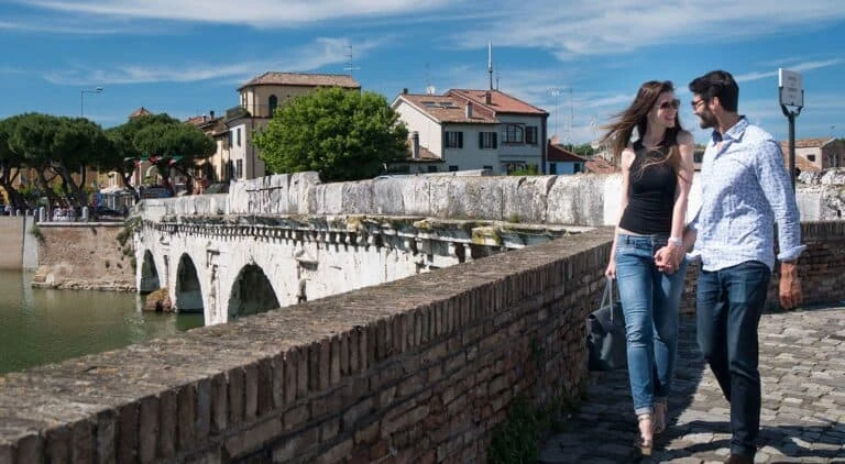 Coppia che passeggia accanto al Ponte di Tiberio a Rimini.