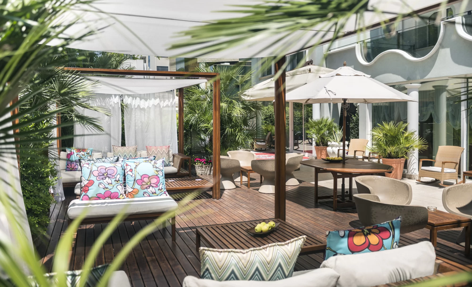 Terrazza all'aperto con arredi moderni, piante e ombrelloni.