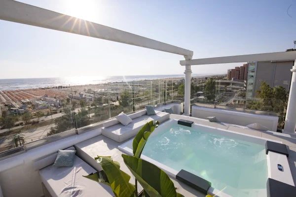 Terrazza con vasca idromassaggio e vista sul mare al tramonto.